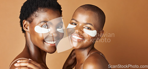 Image of Beauty, eye pads and face of black women in studio with glowing, natural and facial routine. Smile, skincare and portrait of African female friends with cosmetic treatment by brown background.