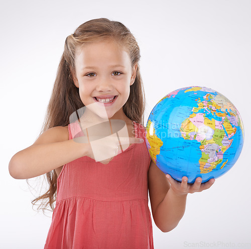 Image of Kid, pointing to globe in studio with world, planets and city for education, geography and portrait. Student, girl child and travel map with smile for earth day support or ecology on white background