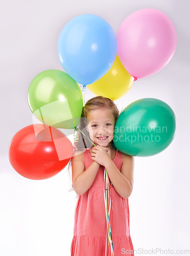 Image of Girl, child and birthday balloons in portrait, party decoration and smiling for milestone event in studio. Happy female person, inflatable accessory and joy on white background, playful and celebrate