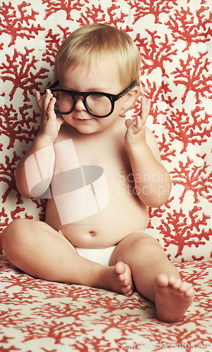 Image of Smile, glasses and fun baby in studio with vision, eye care and health for child development. Happy, cute and young infant, toddler or kid playing with spectacles or eyewear by wallpaper background.