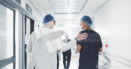 Image of Doctor, nurse and talk while walk in hospital with advice, consult or communication with medical team. People, discuss or coaching for patient care, treatment and wellness after surgery with joke