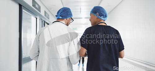 Image of Doctor, nurse and talk while walk in hospital with advice, consult or communication with medical team. People, discuss or coaching for patient care, treatment and wellness after surgery with joke