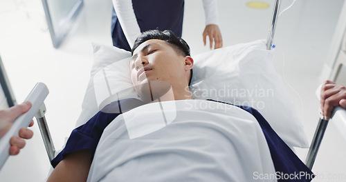 Image of Emergency, bed and man in hospital for medical surgery with team of doctors in clinic corridor for healthcare. Sick, group and person in first aid bed for accident health service or assessment