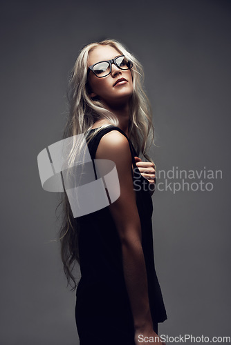 Image of Portrait, woman and glasses in studio with fashion, style and trendy prescription with positive by gray background. Model, confident and eyecare on face with wellness, blonde and elegant aesthetic