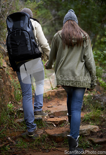 Image of Couple, hiking in nature and holding hands for outdoor adventure and travel journey in a forest or eco woods. Back of People with love, support and walking or trekking in backpack on mountains path