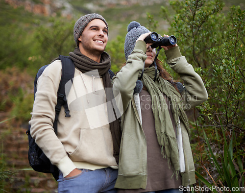 Image of Couple, travel and binoculars in nature for hiking, adventure and journey or explore together in winter. Happy man and woman trekking with outdoor search, vision or birdwatching in forest or woods