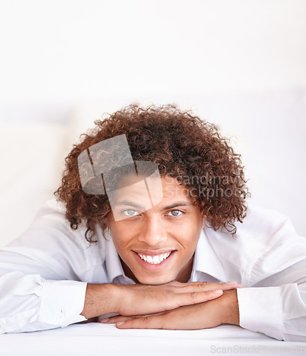 Image of Man, portrait and happy relaxing in bed on weekend, comfortable and lazy or resting in apartment. Male person, face and smiling in bedroom and calm or peace on holiday or vacation in Amsterdam