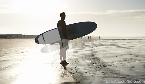 Image of Sunset, surfing and silhouette of man at a beach with surfboard for freedom, travel or sports outdoor. Ocean, training and surfer shadow at sea for swimming, wellness or adventure, workout or holiday