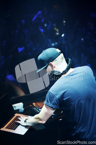 Image of Concert, DJ and man with mixing music by stage and laptop in color spotlight with large crowd. Young person, creative and talented musician in band for sound and performance at event on night club