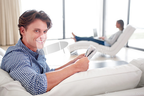 Image of Man, newspaper and portrait on sofa with relax for story, article or information with smile in living room. Person, news or morning routine on couch with print media or knowledge for break in lounge