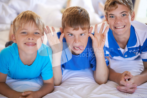Image of Silly, funny and boy children on bed bonding for joke with comic, goofy and comedy faces. Happy, excited and portrait of young kids with crazy and playful facial expression in bedroom at modern home.