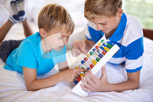 Image of Children, home and playing with abacus for learning, happy and bonding together with educational for math. Brother, teaching and counting game on bed with sibling love, care and development in house