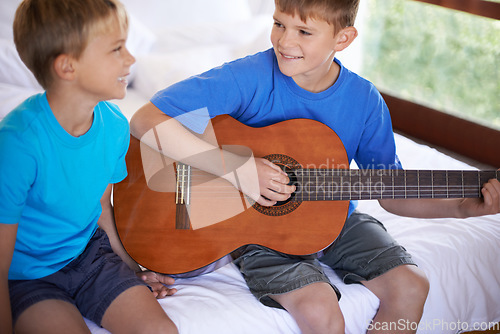 Image of Children, music and siblings on a bed with guitar for playing, bonding or learning together in their home. Musical instrument, love and kids in bedroom with acoustic sound, teaching or having fun