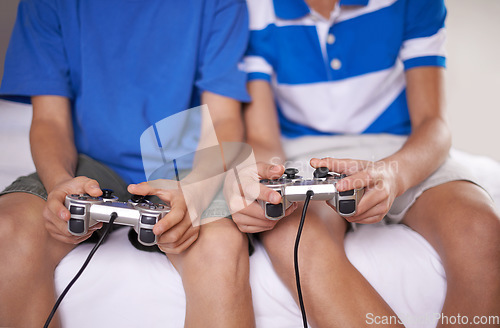 Image of Video game, hands and closeup of children with controllers on bed for entertainment together. Gamers, console and zoom of boy kid friends playing online for fun or hobby sitting in bedroom of home.