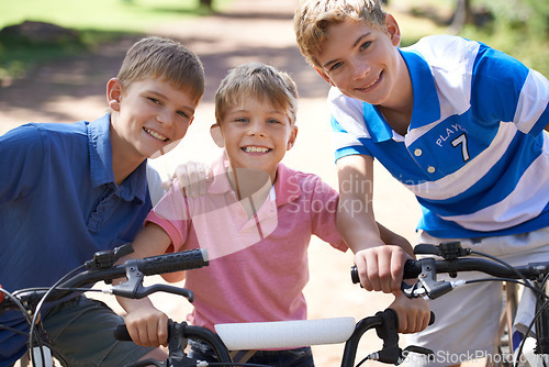 Image of Brothers, bicycle and portrait for together in park, playing and excited for fun outdoor on vacation. Young children, face and bike riding for skill development, love and bonding in summer on holiday