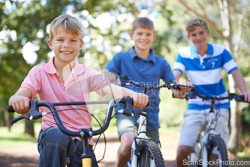 Image of Nature, smile and portrait of kids on bicycles riding in outdoor field, park or forest for exercise. Happy, cycling and confident young boy children on bikes for cardio, hobby or training in a garden