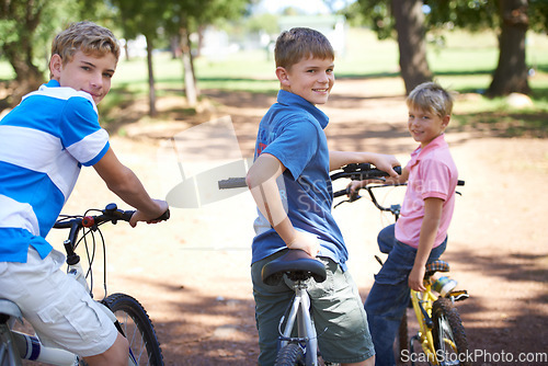 Image of Nature, happy and portrait of kids on bicycles riding in outdoor field, park or forest for exercise. Smile, cycling and confident young boy children on bikes for cardio, hobby or training in a garden