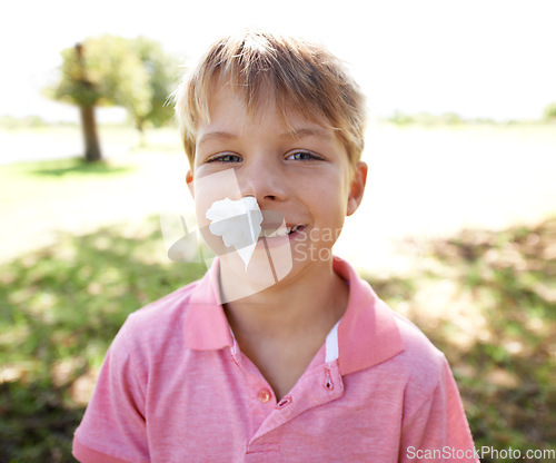 Image of Child, portrait and nose bleed or paper for outdoor adventure or accident, injury or smile. Kid, boy and happy face with tissue for blood on forest playground for physical activity, sports or nature