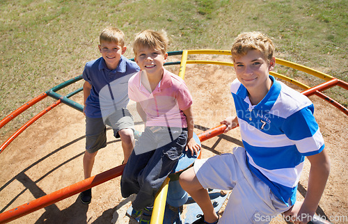 Image of Friends, brothers and playing at park in portrait, kids and smile on merry go round at playground. Happy siblings, carousel and bonding on outdoor adventure, boys and active on vacation or holiday