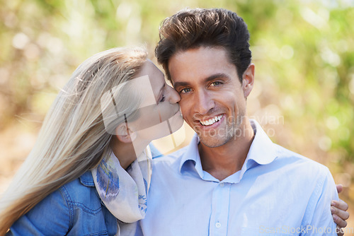 Image of Happy couple, portrait and kiss on cheek in nature for love, bonding or support in relax for outdoor affection. Face of young woman and man smile for embrace, intimacy or romance in forest together