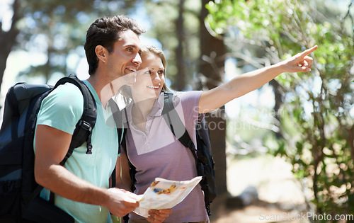 Image of Couple, hiking in nature and map for direction, documents guide or location information of forest travel or journey. Man and woman trekking with infographics, search woods and pointing to destination