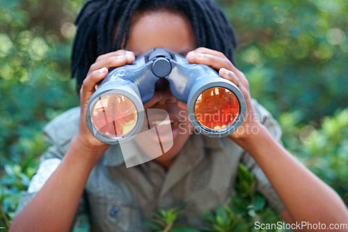 Image of Boy, kid with binoculars and surprise, search in nature for learning and fun, forest and adventure at summer camp. Young African camper, leaves and explore environment outdoor with wow for discovery
