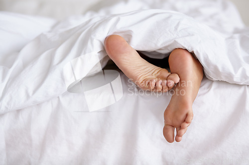 Image of Bed, feet and person sleeping in home, relax and resting nap in sheets for health, calm and leisure in the morning. Foot, bedroom and closeup of toes in blanket, skin of legs and comfort in house