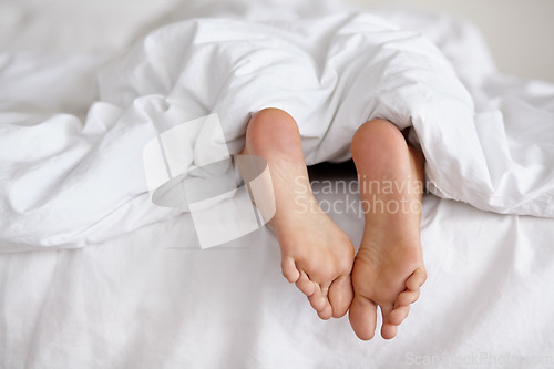 Image of Bed, foot and person sleeping in home, relax and resting nap in sheets for health, calm and leisure in the morning. Feet, bedroom and closeup of toes in blankets, skin of legs and comfort in house