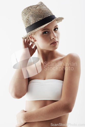 Image of Young model, portrait and straw hat in studio, confident and trendy summer accessory by white background. Blonde woman, face or pride for healthy body in funky clothes, feminine or slender in bikini