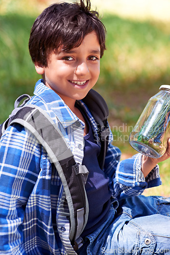 Image of Boy, child and smile with jar in nature, exploring and learning on adventure, hiking in park or woods for fun. Portrait, happy and young explorer, discovery and glass container for collecting bugs