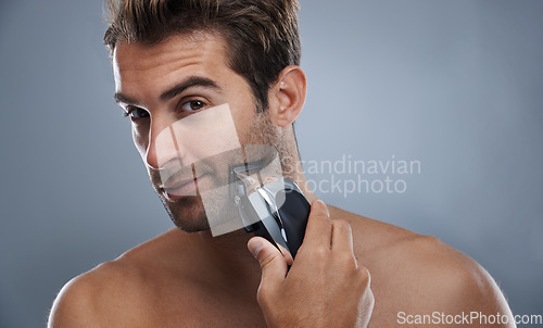 Image of Man, beard and electric razor in studio portrait for grooming, skincare and wellness by grey background. Person, model and shaving with hygiene, facial hair removal and product for cosmetic change