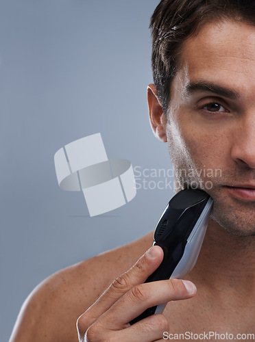 Image of Man, electric shaver and face with closeup studio portrait, grooming and skincare by grey background. Person, model and shaving beard with hygiene, facial hair removal or mockup for cosmetic change