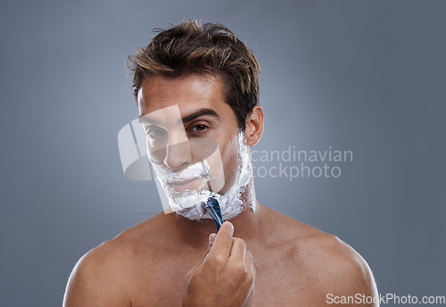 Image of Man, razor and face with shaving in studio portrait for grooming, skin and wellness by grey background. Person, model and blade with cream, facial hair removal and foam product for hygiene with beard