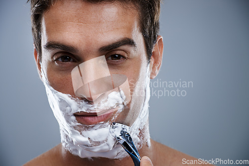 Image of Man, razor and shaving in studio closeup for grooming, skincare and beard in portrait by grey background. Person, model and self care with cream, facial hair removal and product for cosmetic change