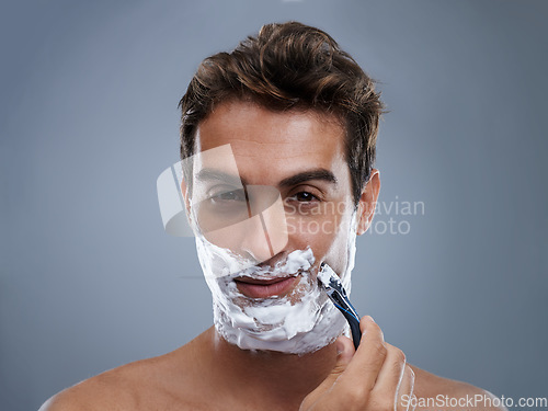 Image of Man, razor and shaving beard in studio portrait for grooming, skincare and wellness by grey background. Person, model and blade with cream, facial hair removal and foam product for cosmetic change