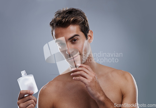 Image of Studio, portrait and man with aftershave for skincare, grooming and facial treatment or cologne. Model, face and happy with bottle for cosmetics product, fragrance and male beauty by gray background