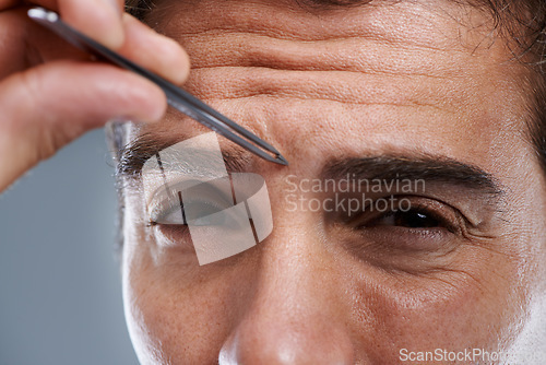 Image of Man, portrait and tweezers for eyebrows in studio or face grooming, hygiene or grey background. Male person, tools and painful hair removal for healthy morning routine or cosmetics, treatment or care