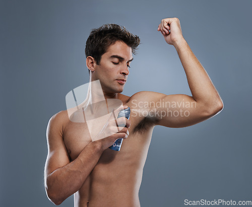 Image of Man, deodorant and spray for armpit or smell in studio or product application for clean odor, hygiene or grey background. Male person, topless and confidence or health wellness, care or mockup space