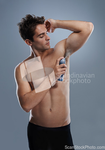 Image of Man, deodorant and cleaning armpit for smell in studio or product application for odor, hygiene or grey background. Male person, topless and confidence or health wellness, self care or mockup space