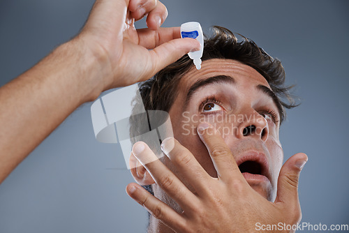Image of Man, eye drops and vision for allergies care in studio or healthcare wellness, liquid or grey background. Male person, solution and conjunctivitis dropper for clean pupil or dry, irritation or mockup