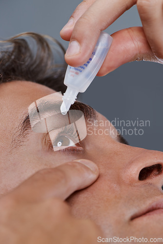 Image of Man, eye drops and vision for allergies or treatment in studio or healthcare wellness, dropper or grey background. Male person, solution and conjunctivitis for clean pupil or pain, liquid or apply