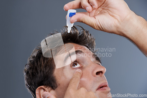 Image of Man, eye drops and vision for allergies or liquid in studio or healthcare wellness, dropper or grey background. Male person, solution and conjunctivitis for clean pupil or fluid, irritation or mockup