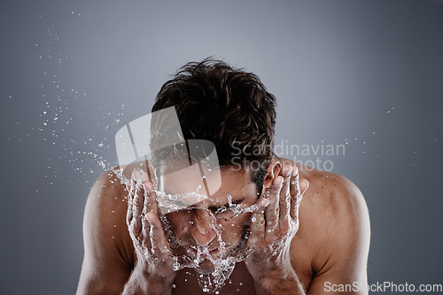 Image of Water splash, studio and man wash face for self care routine, morning facial cleanse or skincare. Liquid, wellness and person with hygiene treatment, grooming and skin cleaning on grey background