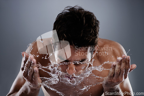 Image of Water, splash and man wash face for bathroom routine, morning facial cleanse or skincare. Studio, wellness and wet model with hygiene treatment, grooming and skin cleaning on grey background