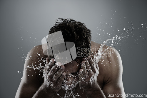 Image of Water, splash and man cleaning face for bathroom routine, cleanse or fresh skincare in morning beauty treatment. Studio, skin hydration and model facial wash, hygiene and grooming on grey background