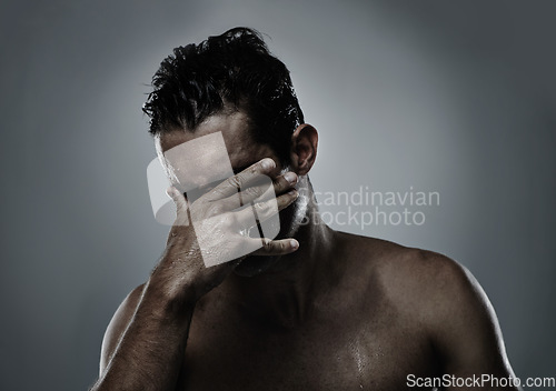 Image of Man, hand and face hiding in studio for embarrassed shame on grey background or topless, unhappy or mockup space. Male person, model and fingers for bad decision or fail mistake, palm or distress