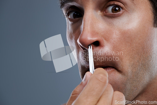 Image of Man, nose and hair with tweezers in studio on grey background for self care, wellness or dermatology. Male person, face and grooming for cosmetic beauty or healthy cleaning, wellbeing or mockup space