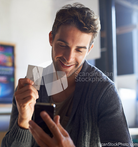 Image of Business card, phone and young man in cafe dial mobile number for communication or call. Smile, contact paper and male person reading email or message on cellphone in coffee shop or restaurant.