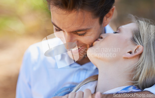 Image of Happy couple, kiss and hug in nature for embrace, love or support in outdoor walk or bonding. Young woman and man with smile on cheek for affection, comfort or romance in forest or woods together