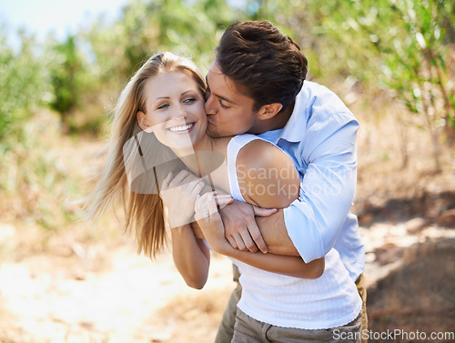 Image of Mwah. Couple, face and happy with kiss in nature or relationship for holiday, vacation or travel. Romance, man and woman with smile outdoor in forest with embrace for bonding, love or relax in woods.